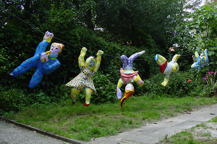 ga verder Preek Arrangement Sculptuur Familie op stap, een sculptuur van polyester bestaand uit 8  kleurrijk beschilderde hangende beelden, te weten: vader, moeder, zoon,  dochter, slangenvrouw, meisje met beer, kat en hond